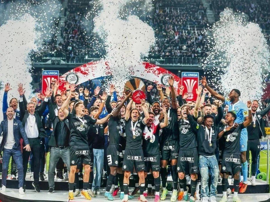 Mannschaft feiert mit dem Pokal im Stadion